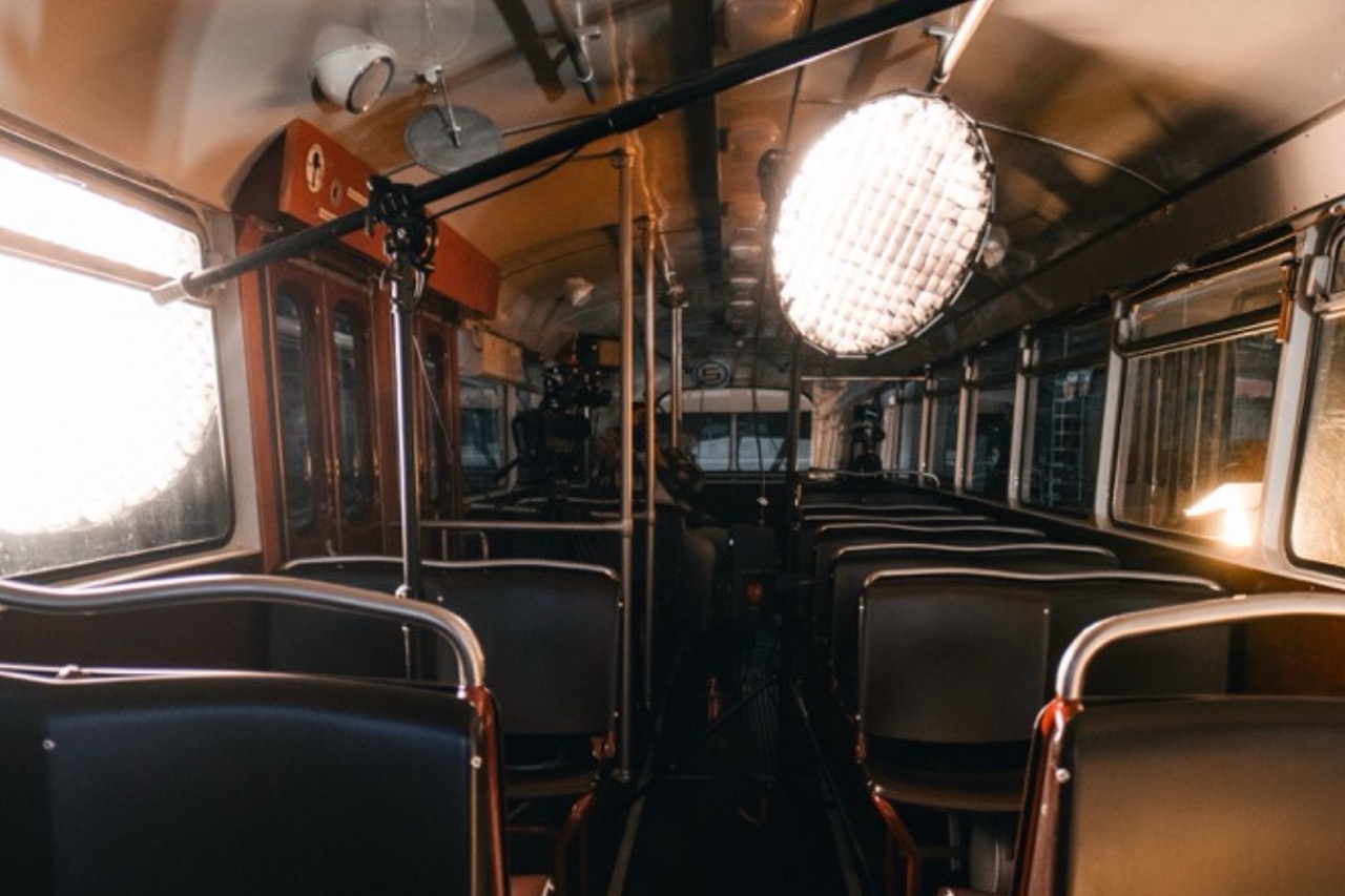 Runde Filmleuchte mit Gitter in einer historischen Straßenbahn neben hellen Fenstern